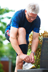 Image showing Senior, tie or runner with shoes on bench in nature for exercise, training or fitness workout. Start, healthy man or mature athlete in park with sports footwear ready for jog, walking or wellness