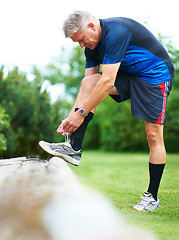 Image showing Senior, tie or runner with shoes on rock by nature for exercise, training or outdoor workout. Fitness, healthy man or mature person in park with sports footwear ready for jog, walking or wellness