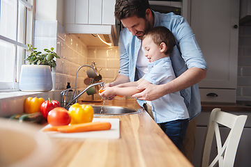 Image showing The first step to preparing a meal. a young boy and his father rinsing vegetables at home.