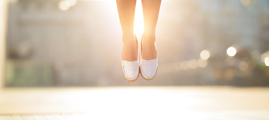 Image showing Get those feet in the air. a woman jumping mid air in happiness.