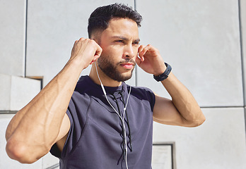 Image showing Im all in. a sporty young man listening to music while exercising outdoors.