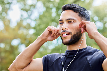 Image showing Music can elevate your mood and motivate you. a sporty young man listening to music while exercising outdoors.