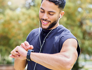 Image showing Set the clock and just go for your goals. a sporty young man listening to music and checking his watch while exercising outdoors.