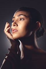 Image showing Her skin is glowing from the inside out. Studio shot of a beautiful young woman posing with light beam against her face.