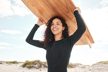 Image showing You can take a surfer out of the surf. an attractive young woman carrying a surfboard at the beach.