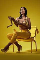 Image showing Just follow the yellow. a fashionable woman holding a snake while modelling a yellow concept.