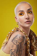 Image showing They should be scared of me. a young woman posing with a snake around her neck against a yellow background.