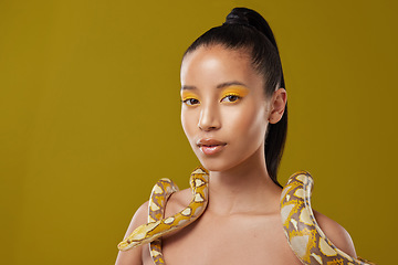 Image showing You can trust me. a young woman posing with a snake around her neck against a yellow background.