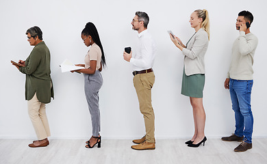 Image showing Full length profile of diverse group of businesspeople standing in line together to wait while using technology and paperwork. Team of professionals queueing in row for an interview for a job vacancy