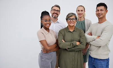 Image showing Portrait of a group of a multiracial business team standing in a group in studio isolated against a grey background. Young and senior work colleagues standing together with their arms crossed