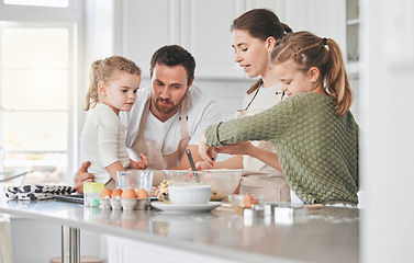 Image showing Everyone gets a turn to whisk. a family baking together in the kitchen.