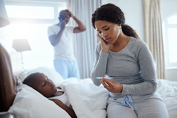 Image showing The most important thing in the world is family. a woman taking her little boys temperature with a thermometer in bed at home.