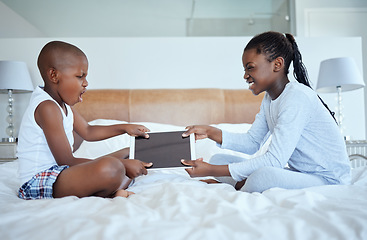 Image showing Sibling wars. two siblings fighting in a game of tug of war over their digital tablet.