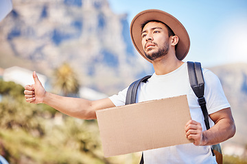 Image showing Help me please. a young man holding a blank sign while hitchhiking on the side of the road.