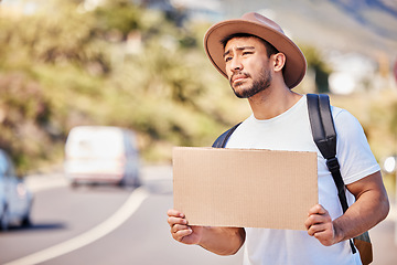 Image showing I hope someone stops for me. a young man holding a blank sign while hitchhiking on the side of the road.