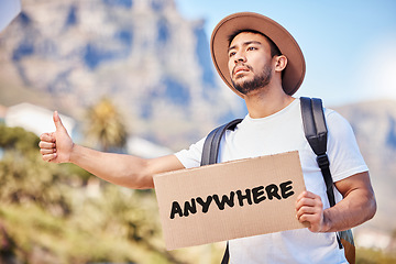 Image showing Ill go anywhere. a young man holding a sign that reads anywhere while hitchhiking on the side of the road.