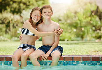 Image showing We spend most of our day by the pool. a young boy and girl sitting with their feet in the pool.