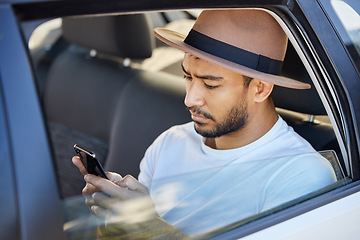 Image showing If you’re on a road trip, you need driving music. a young man sitting in a car while using his phone.