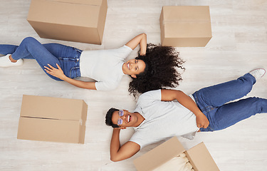 Image showing New beginnings loading. a young couple lying on the floor while unpacking boxes in their new house.