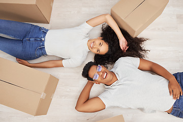 Image showing Starting a new life. a young couple lying on the floor while unpacking boxes in their new house.