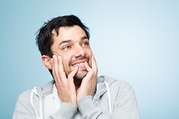 Image showing Thinking of silly things. a young man touching his face against a studio background.