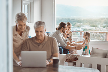 Image showing Lets sit and wait for the surprise Grandpa has to show us. a senior couple using a laptop while a young family sits in the background.