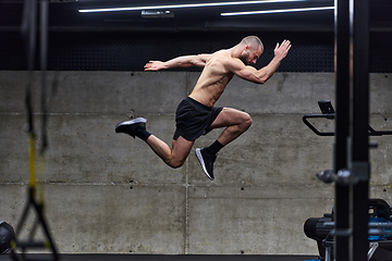 Image showing A muscular man captured in air as he jumps in a modern gym, showcasing his athleticism, power, and determination through a highintensity fitness routine