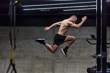 Image showing A muscular man captured in air as he jumps in a modern gym, showcasing his athleticism, power, and determination through a highintensity fitness routine