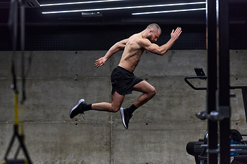 Image showing A muscular man captured in air as he jumps in a modern gym, showcasing his athleticism, power, and determination through a highintensity fitness routine