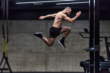 Image showing A muscular man captured in air as he jumps in a modern gym, showcasing his athleticism, power, and determination through a highintensity fitness routine