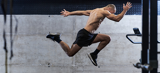 Image showing A muscular man captured in air as he jumps in a modern gym, showcasing his athleticism, power, and determination through a highintensity fitness routine