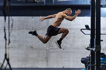 Image showing A muscular man captured in air as he jumps in a modern gym, showcasing his athleticism, power, and determination through a highintensity fitness routine