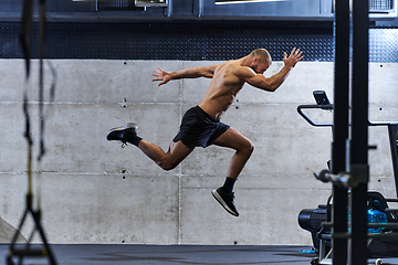 Image showing A muscular man captured in air as he jumps in a modern gym, showcasing his athleticism, power, and determination through a highintensity fitness routine