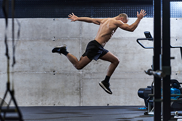 Image showing A muscular man captured in air as he jumps in a modern gym, showcasing his athleticism, power, and determination through a highintensity fitness routine