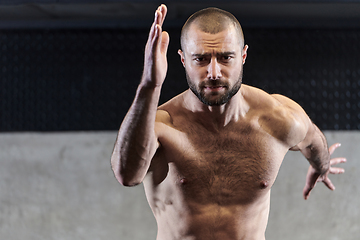 Image showing A muscular man standing in the starting position for running, exuding determination and readiness for an intense fitness workout or athletic competition.