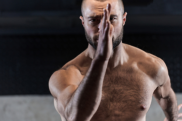 Image showing A muscular man standing in the starting position for running, exuding determination and readiness for an intense fitness workout or athletic competition.