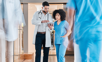 Image showing Less paperwork means more time for patient care. two young doctors using a tablet and having a discussion in a modern office.