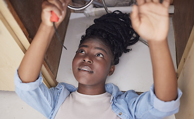 Image showing Nothing in the world can take the place of perseverance. a young woman installing a kitchen sink at home.