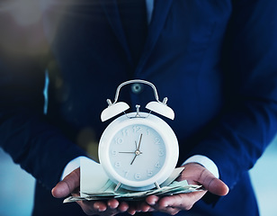 Image showing Time is precious. an unrecognisable businessman standing alone in the office and holding an alarm clock.