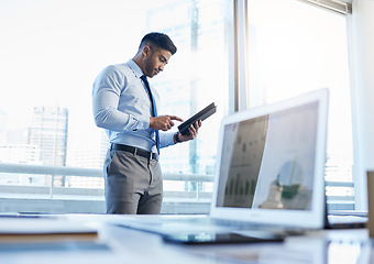 Image showing Theres no excuse not to be ahead of the game. a businessman using a digital tablet while standing in his office.