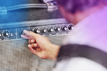 Image showing Pump up the volume. an unrecognizable male performer adjusting his amp during a concert.