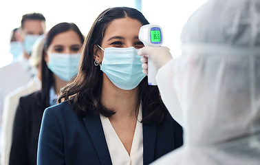 Image showing Making sure youre good to go. a group of businesspeople standing in a line to get their temperatures read.