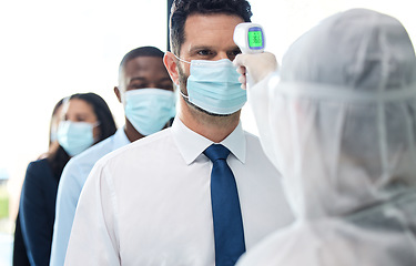 Image showing You can only enter if your temperatures regular. a group of businesspeople standing in a line to get their temperatures read.