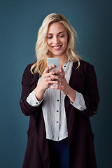 Image showing Its all about contacting the correct clients. Studio shot of a beautiful young businesswoman using a cellphone against a blue background.