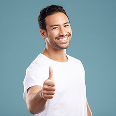 Image showing Handsome young mixed race man giving thumbs up while standing in studio isolated against a blue background. Hispanic male showing support or appreciation. Backing or endorsing a product or company