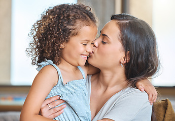Image showing Loving mother embracing her daughter and gently kissing her on the cheek showing love and affection while sitting on the couch at home. Sweet moment between mother and child showing love and affectio