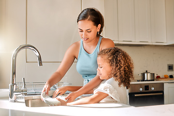 Image showing Little girl helping her mother with household chores at home. Happy mom and daughter washing dishes in the kitchen together. Kid learning to be responsible by doing tasks