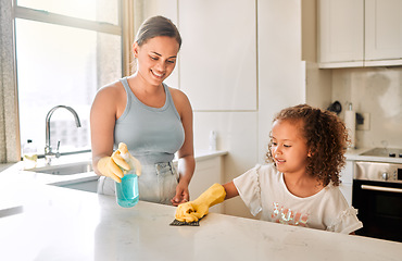 Image showing Little girl helping her mother with household chores at home. Happy mom and daughter wearing gloves while spraying and scrubbing the kitchen counter together. Kid learning to be responsible by doing