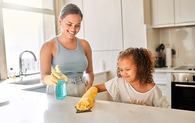 Image showing Little girl helping her mother with household chores at home. Happy mom and daughter wearing gloves while spraying and scrubbing the kitchen counter together. Kid learning to be responsible by doing