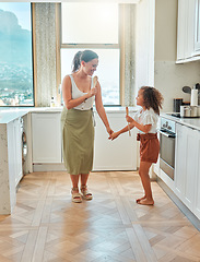 Image showing Mother and little daughter singing and dancing in the kitchen. Mixed race mom and child holding wooden spoons while having fun at home